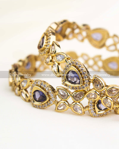 Close-up showing intricate AD work and teardrop purple stones on gold-finished Victorian bangles.