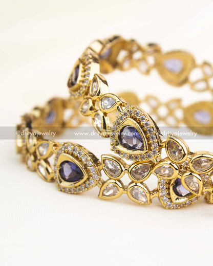 Close-up showing intricate AD work and teardrop purple stones on gold-finished Victorian bangles.