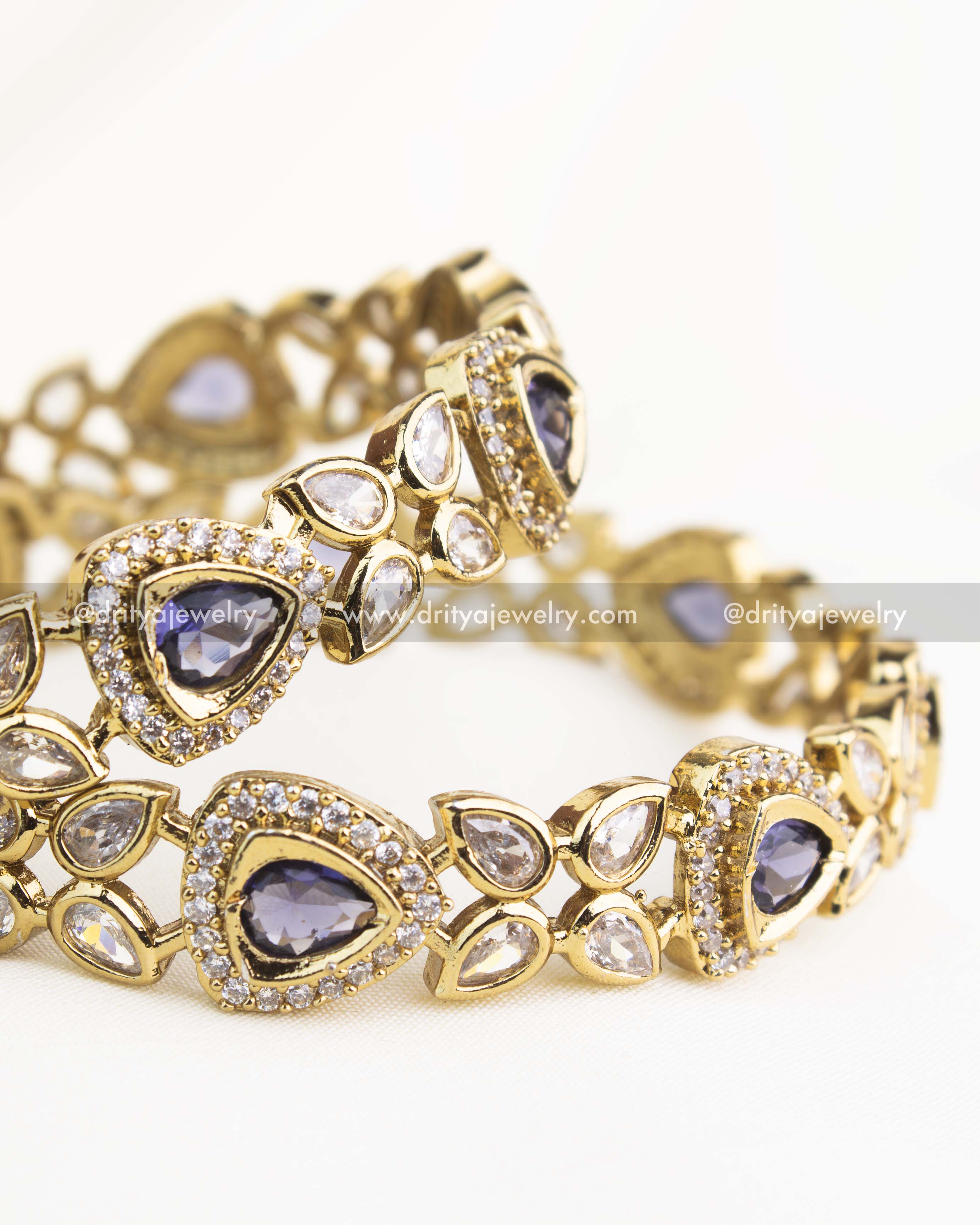 Close-up showing intricate AD work and teardrop purple stones on gold-finished Victorian bangles.