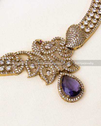 Detailed peacock design with a teardrop purple gemstone in a Victorian gold finish.