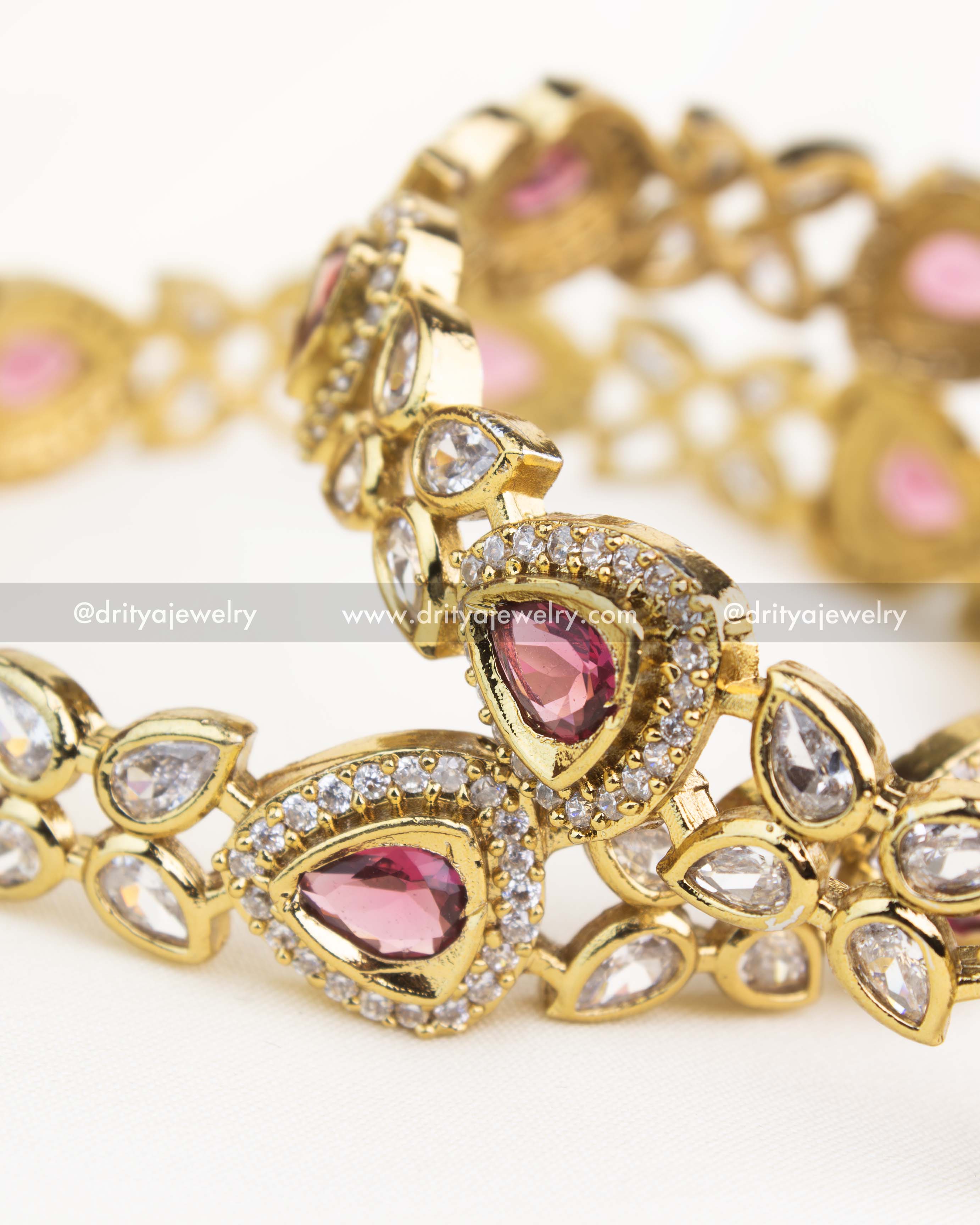 Detailed close-up of ruby red AD stone bangles featuring pear-shaped gems and Victorian gold polish.
