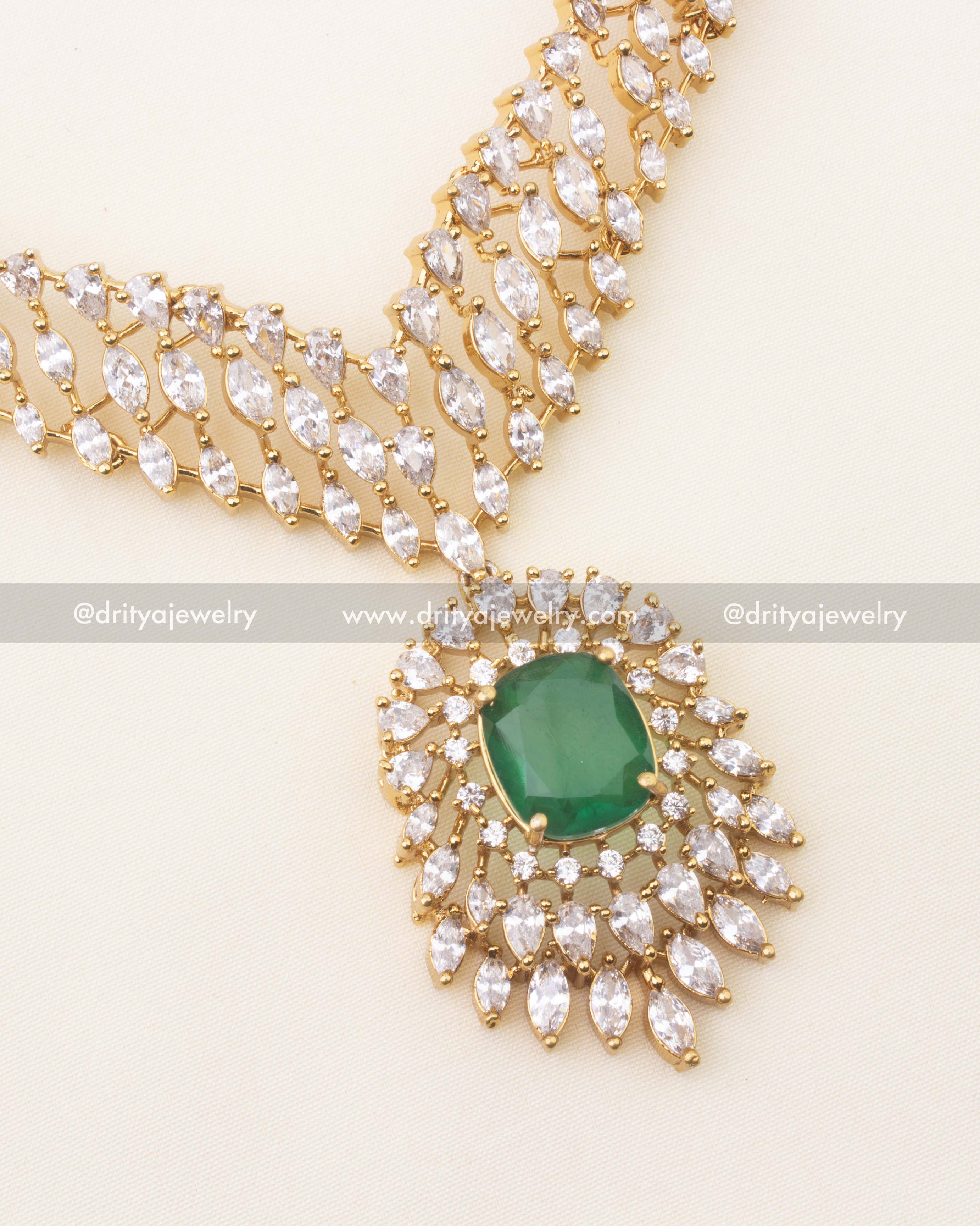 Detail view of emerald‑green stone framed by marquise and round CZ stones on V‑link necklace.