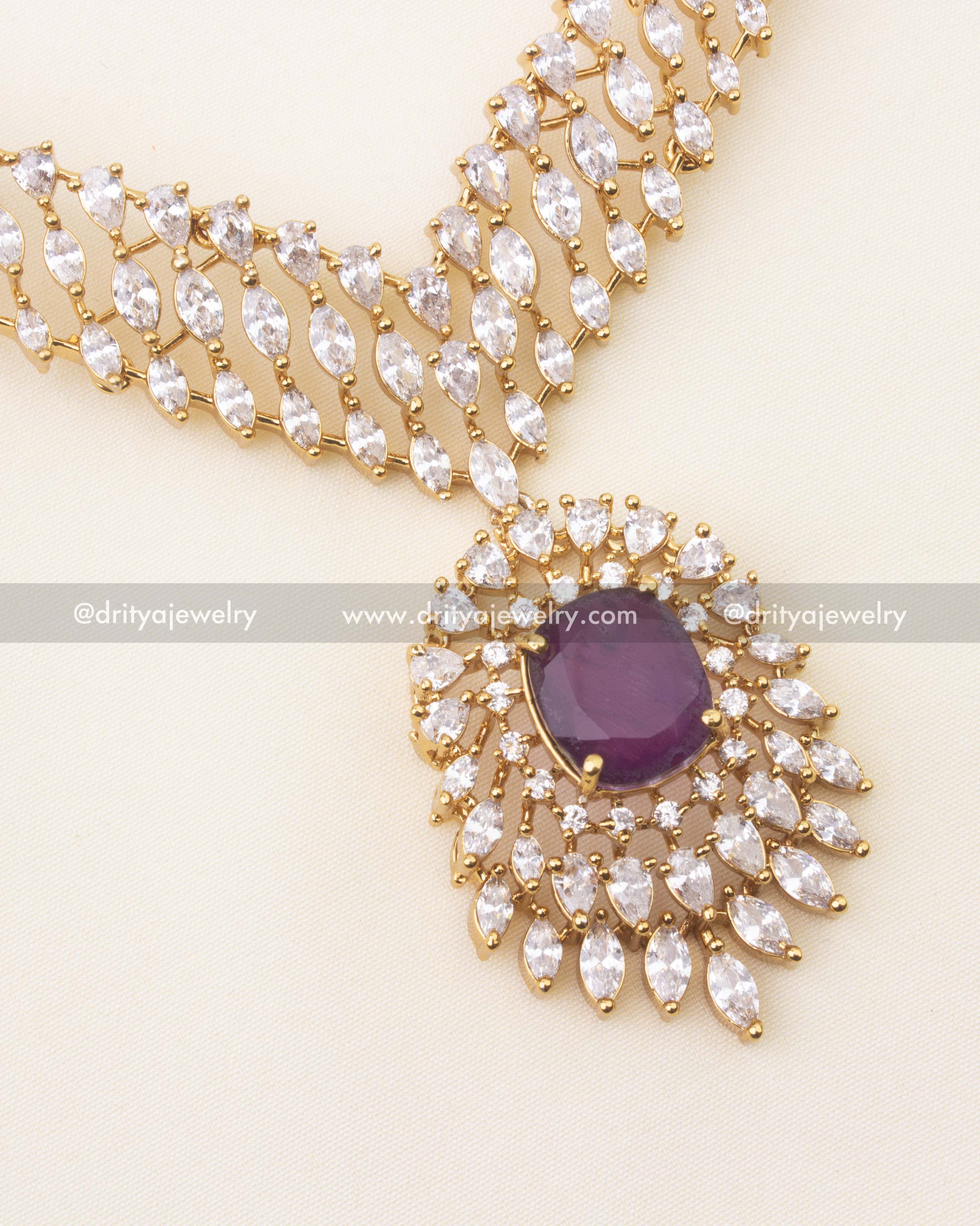 Detail of purple center stone surrounded by marquise and round CZ stones on V‑link necklace.