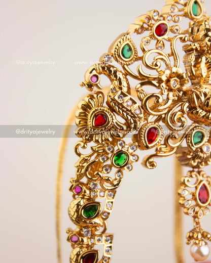 Detailed view of peacock motif with ruby, emerald, and CZ stone embellishments on temple vanki.