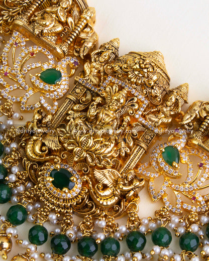Detailed view of the pendant highlighting Lakshmi Devi, temple structure, green stone accents, and cascading green and pearl bead drops.