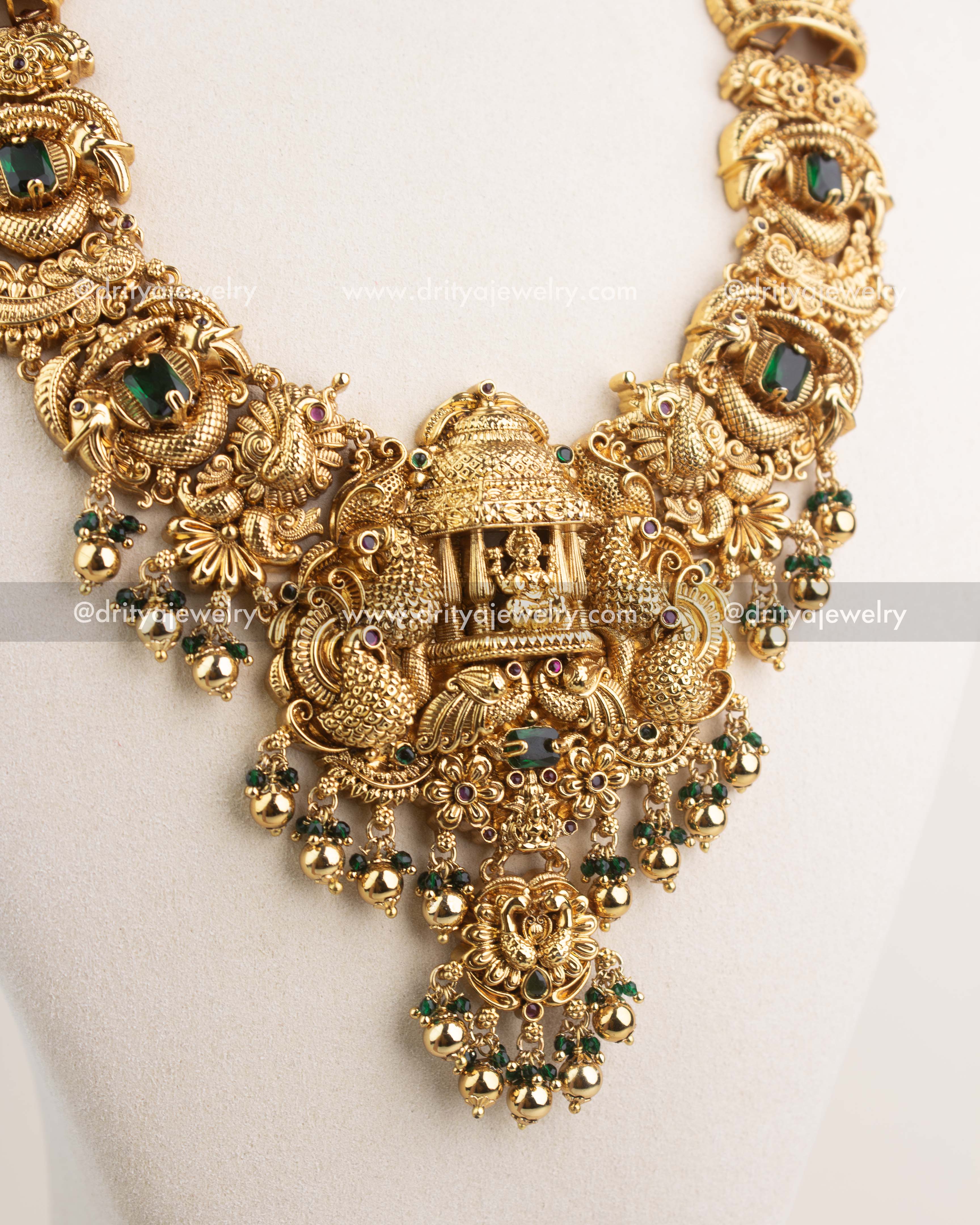 Detailed image of temple-style pendant with Lakshmi motif, peacocks, and emerald green accents.