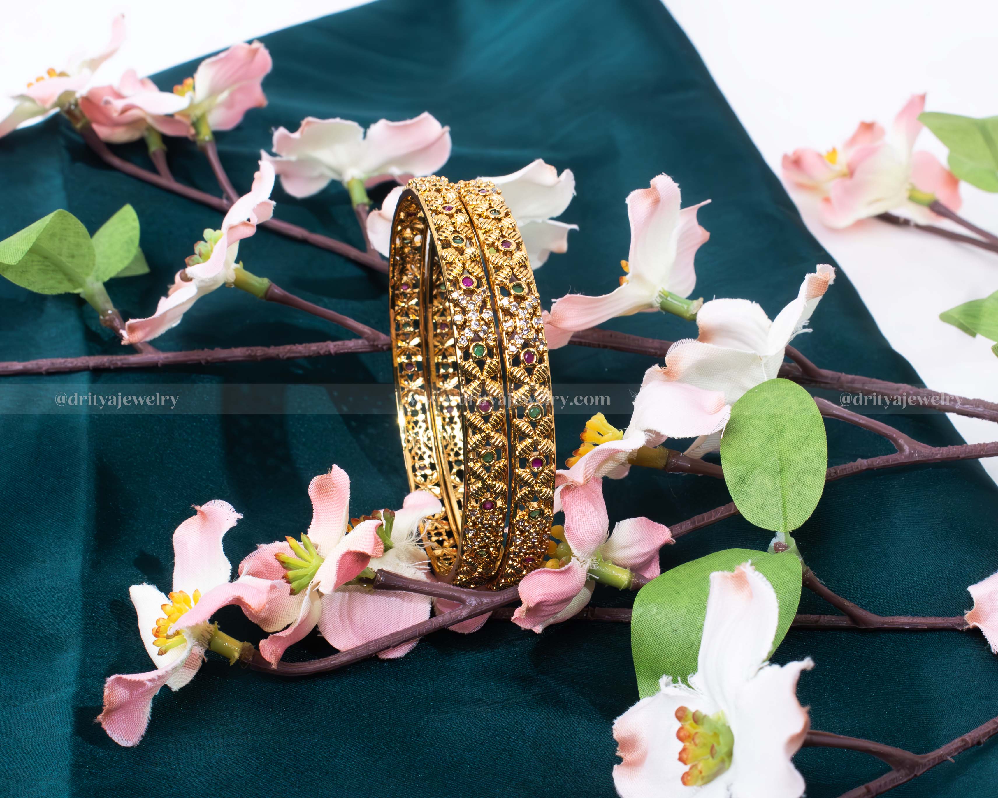 Opulent golden bangle set adorned with rubies, emeralds, and intricate carvings by Dritya Jewelry.