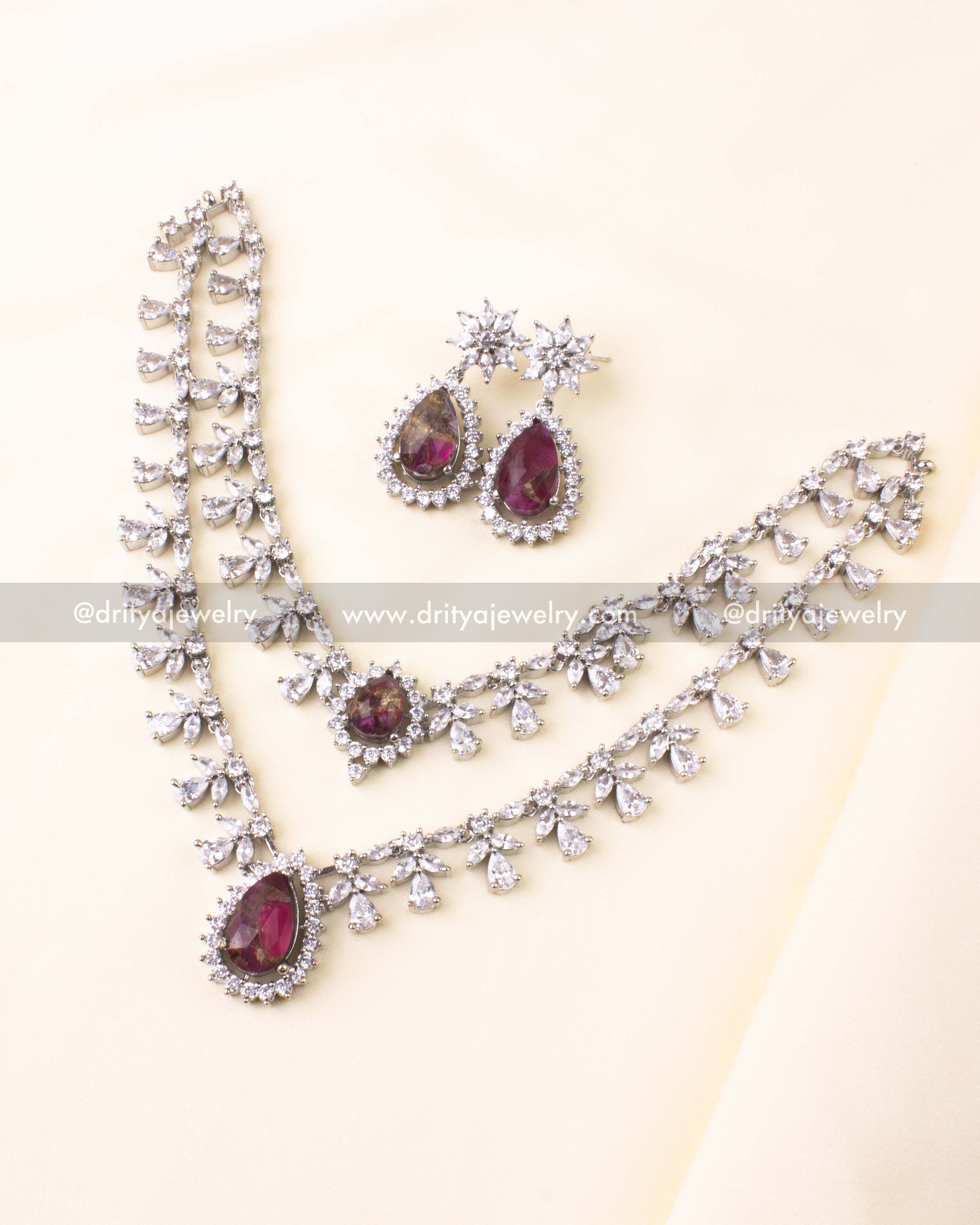 Silver-plated necklace with dual chains, magenta teardrop pendant, and CZ detailing.