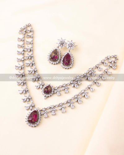 Silver-plated necklace with dual chains, magenta teardrop pendant, and CZ detailing.