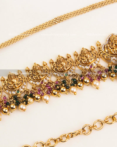 Detailed Nakshi hip chain with ruby and green stone highlights, antique polish, and pearl drops.