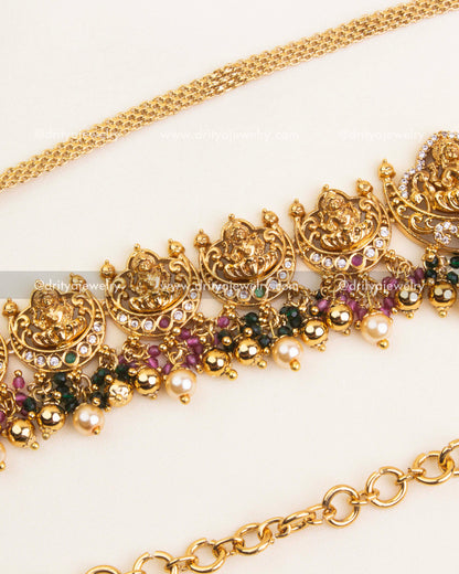 Detailed Nakshi hip chain with ruby and green stone highlights, antique polish, and pearl drops.