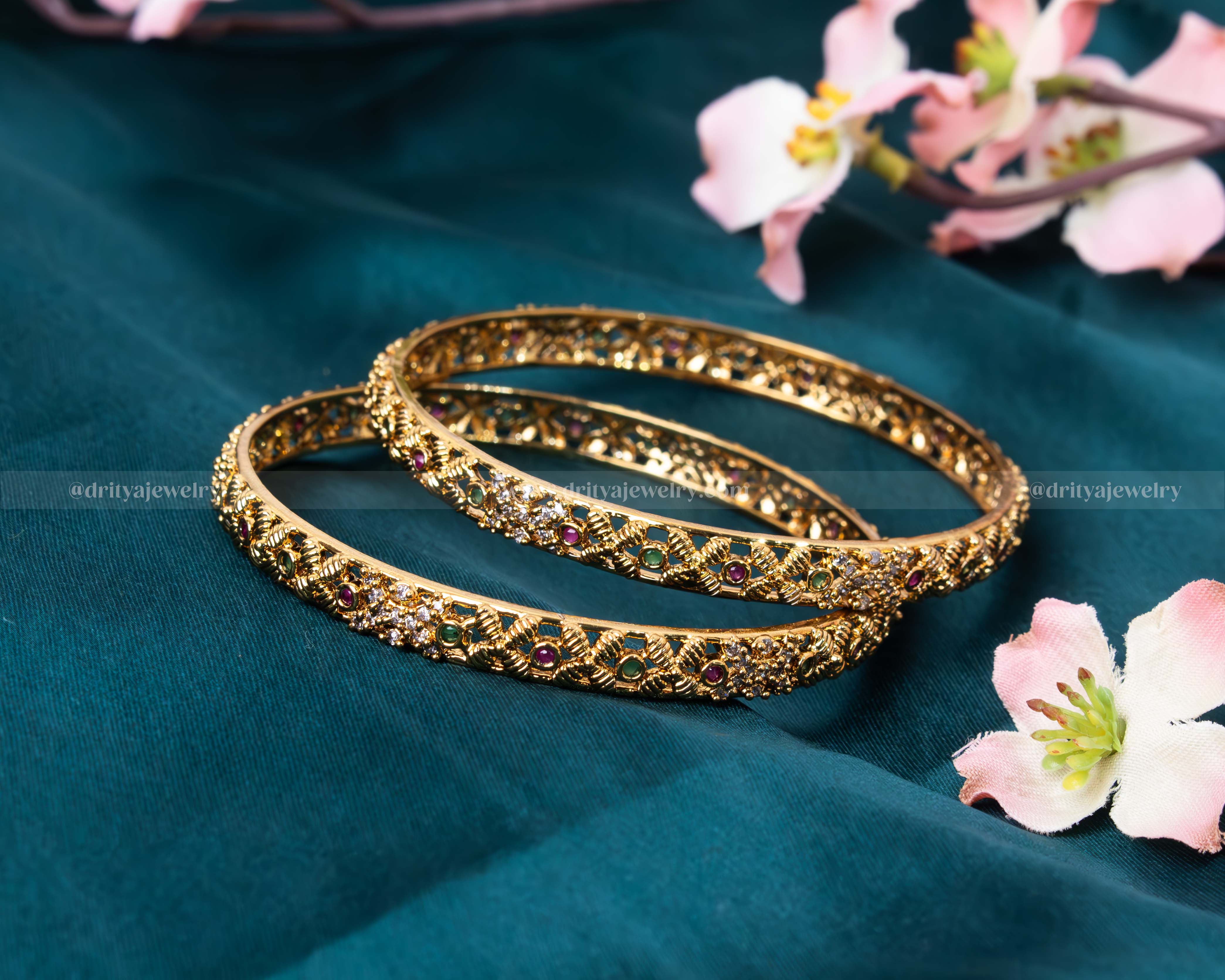 Close-up of Dritya Jewelry’s golden bangles showcasing exquisite gemstone details and golden carvings.