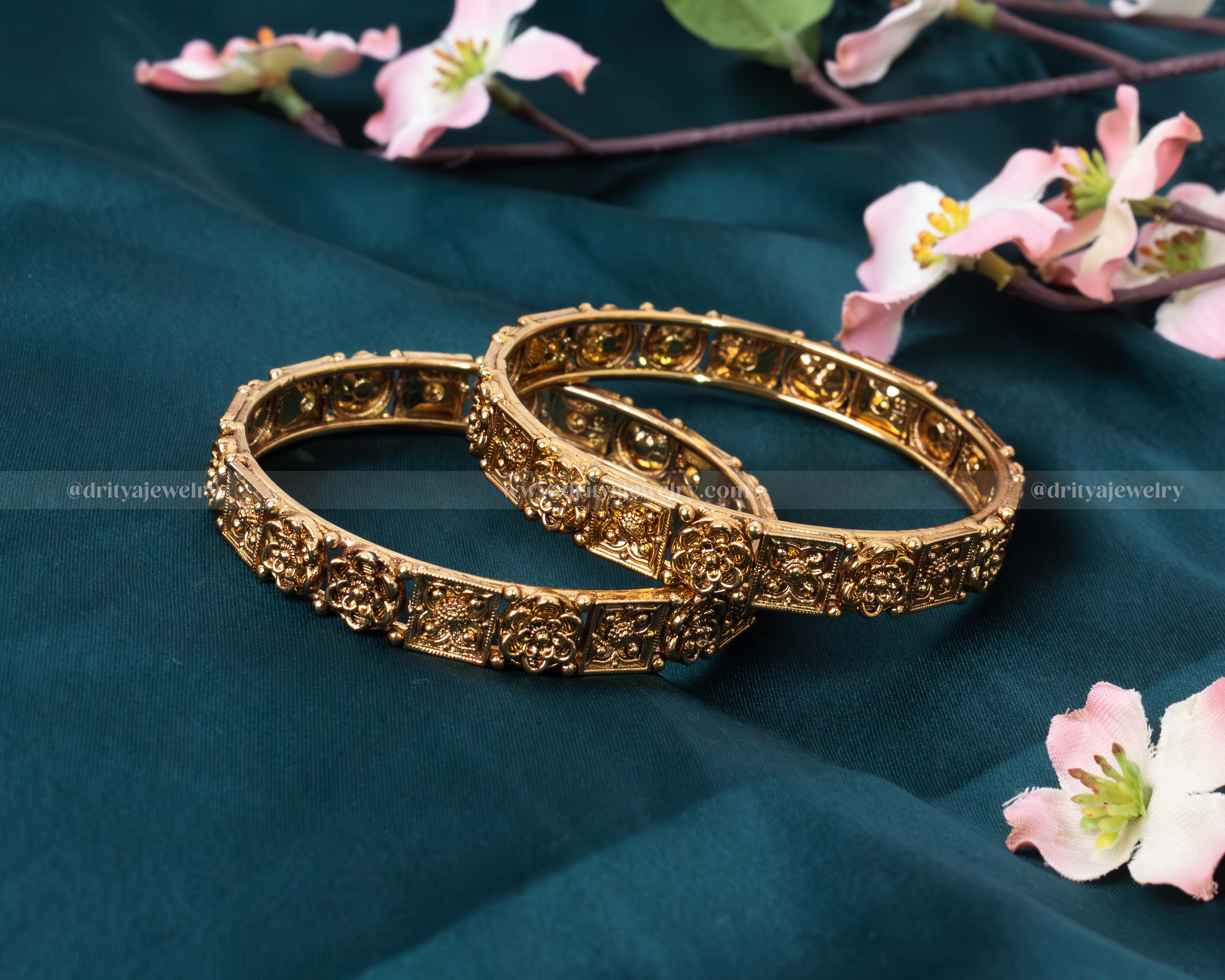 Close-up view of the detailed carvings and antique gold finish on Dritya Jewelry’s openable bangle set.