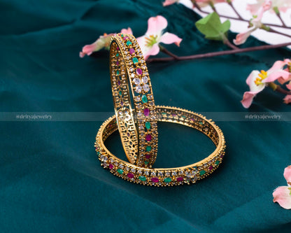 Close-up of a gold bangle showing detailed gem placement and intricate design by Dritya Jewelry.