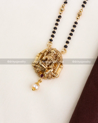 Close-up of Nakshi Lakshmi Devi pendant with ruby stone and pearl drop on black beads chain.