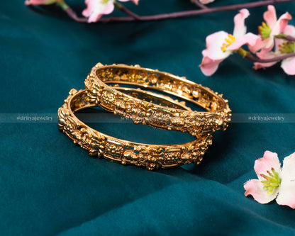 Close-up view of the Lakshmi Devi Temple Bangle showing the intricate traditional motifs and gold finish.