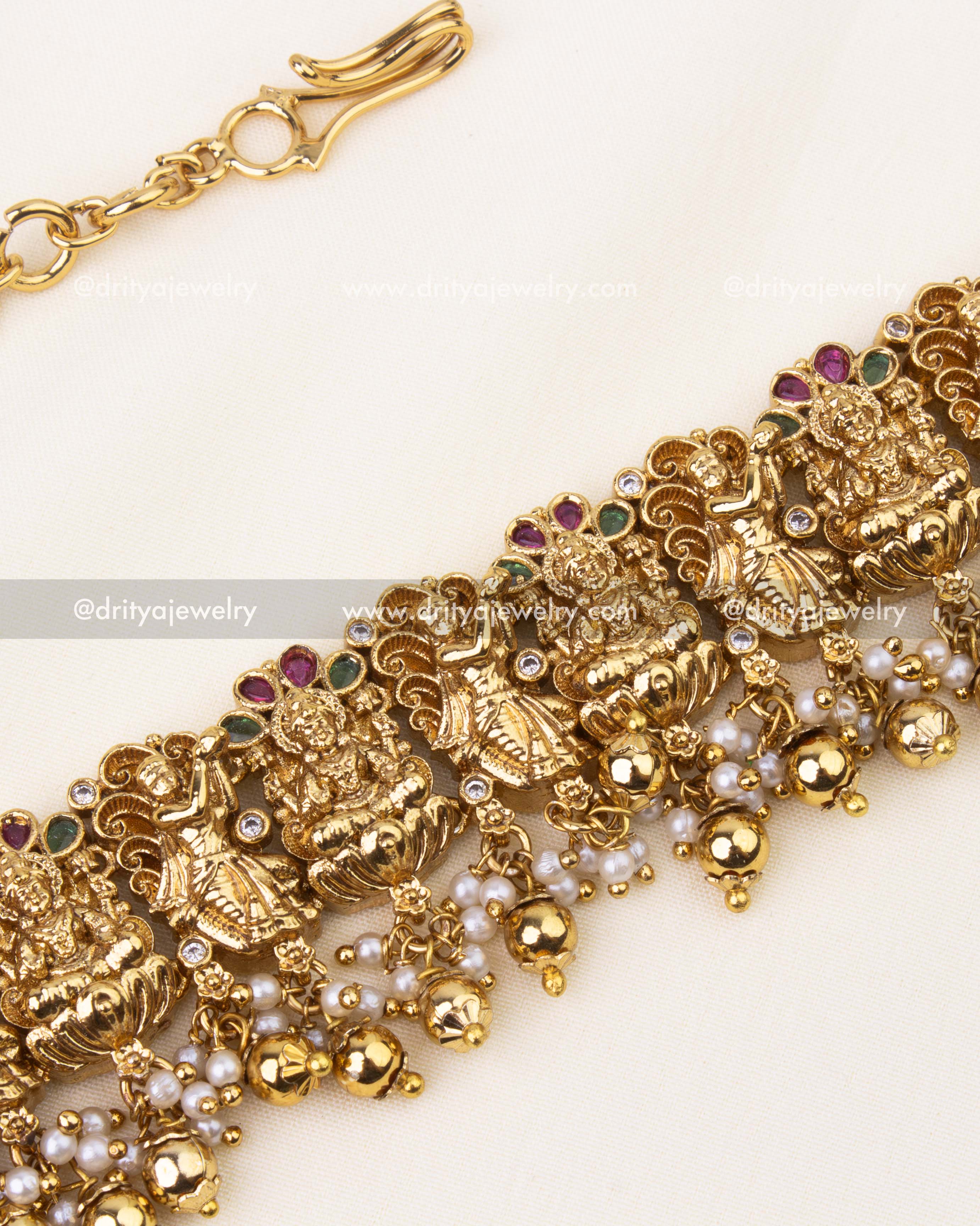 Detailed view of Lakshmi motifs with ruby and emerald stone embellishments.