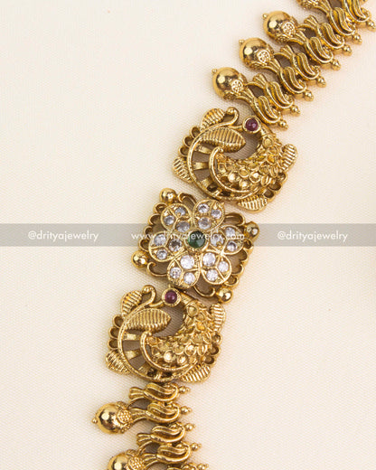 Close-up showing peacock designs, floral patterns, and antique gold polish on the necklace.