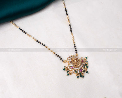 Elegant black beads necklace with a detailed gold Lakshmi Devi pendant adorned with green and pink gemstones, perfect for religious occasions and festive wear.