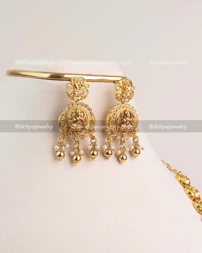 Temple-style Lakshmi Devi earrings with pearl and gold bead hangings in gold finish.