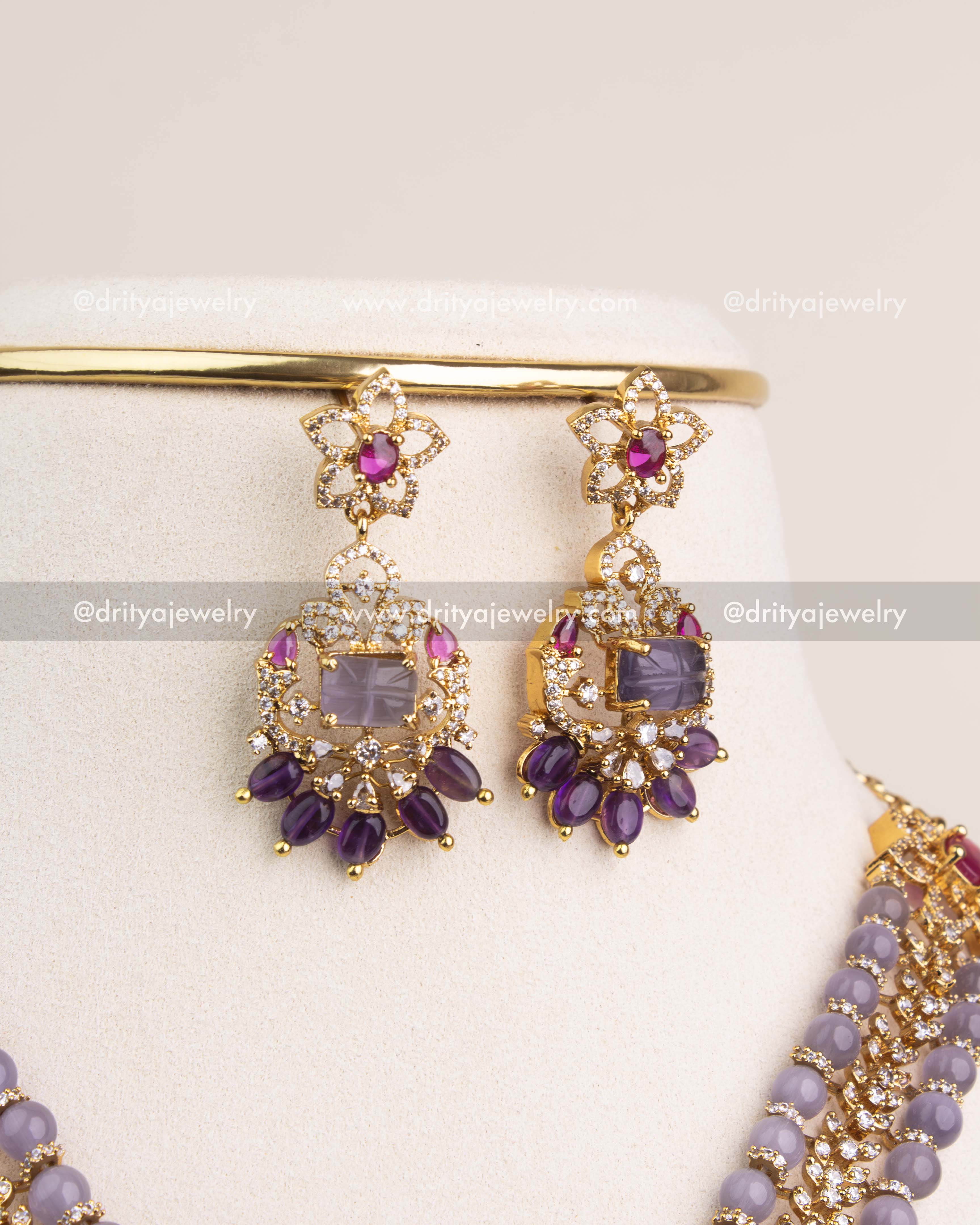 Gold finish earrings with lavender stone center, ruby accents, and amethyst bead drops.