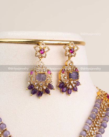 Gold finish earrings with lavender stone center, ruby accents, and amethyst bead drops.