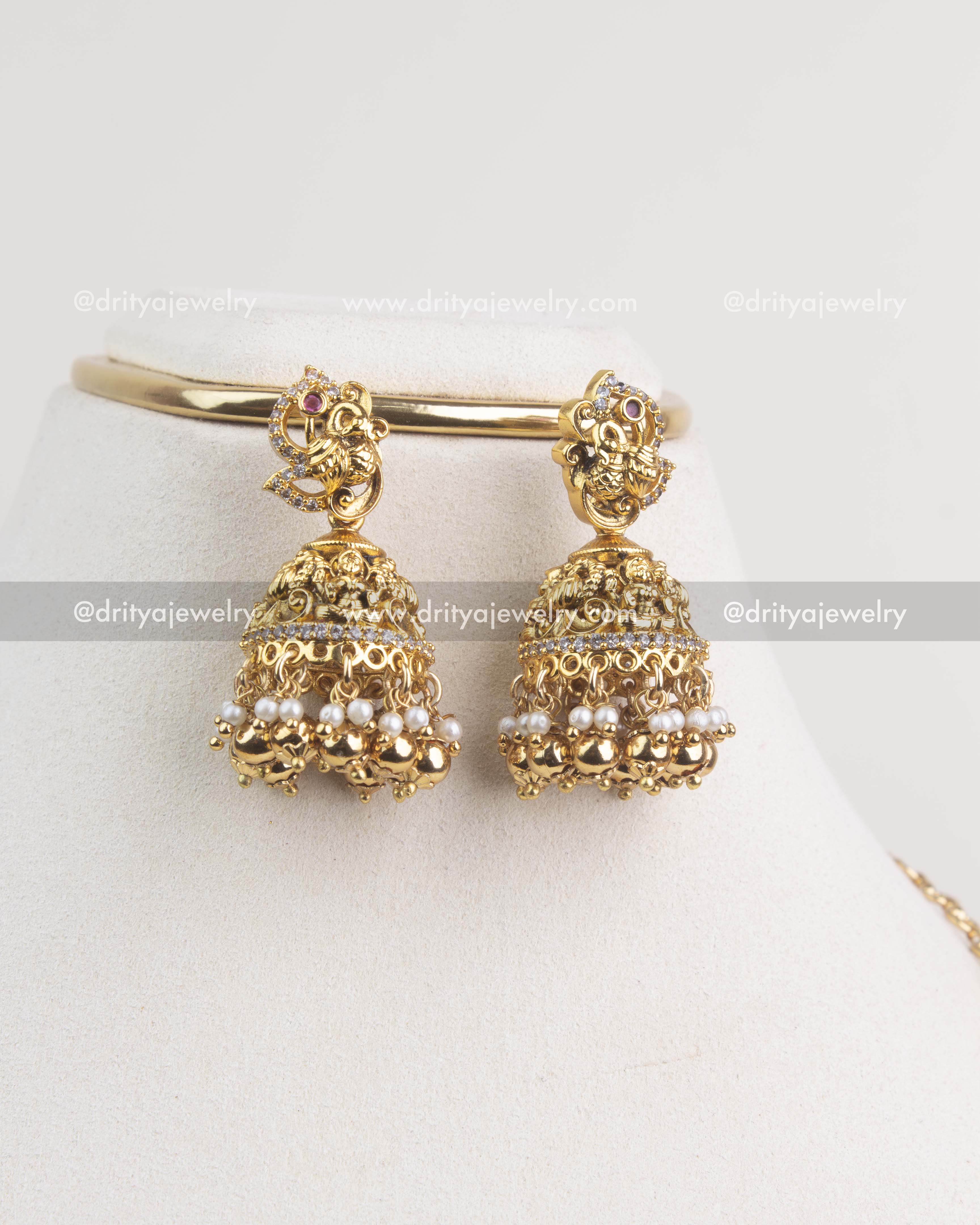 Antique gold jhumkas with Nakshi detailing, pearl drops, and ruby accents.