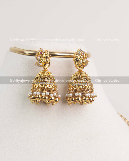 Antique gold jhumkas with Nakshi detailing, pearl drops, and ruby accents.