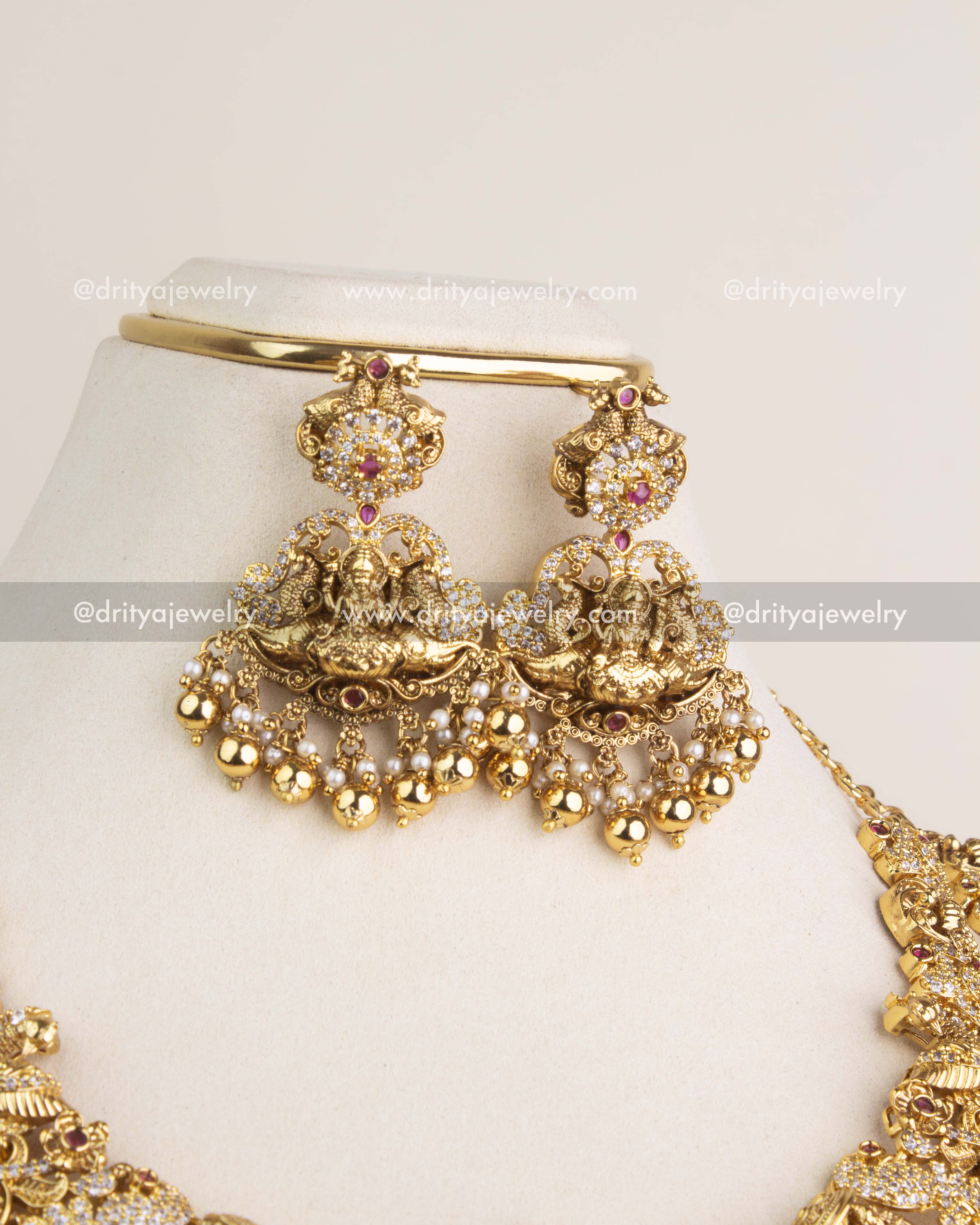 Traditional temple dangler earrings featuring Lakshmi design, ruby kemp accents, and golden bead drops.
