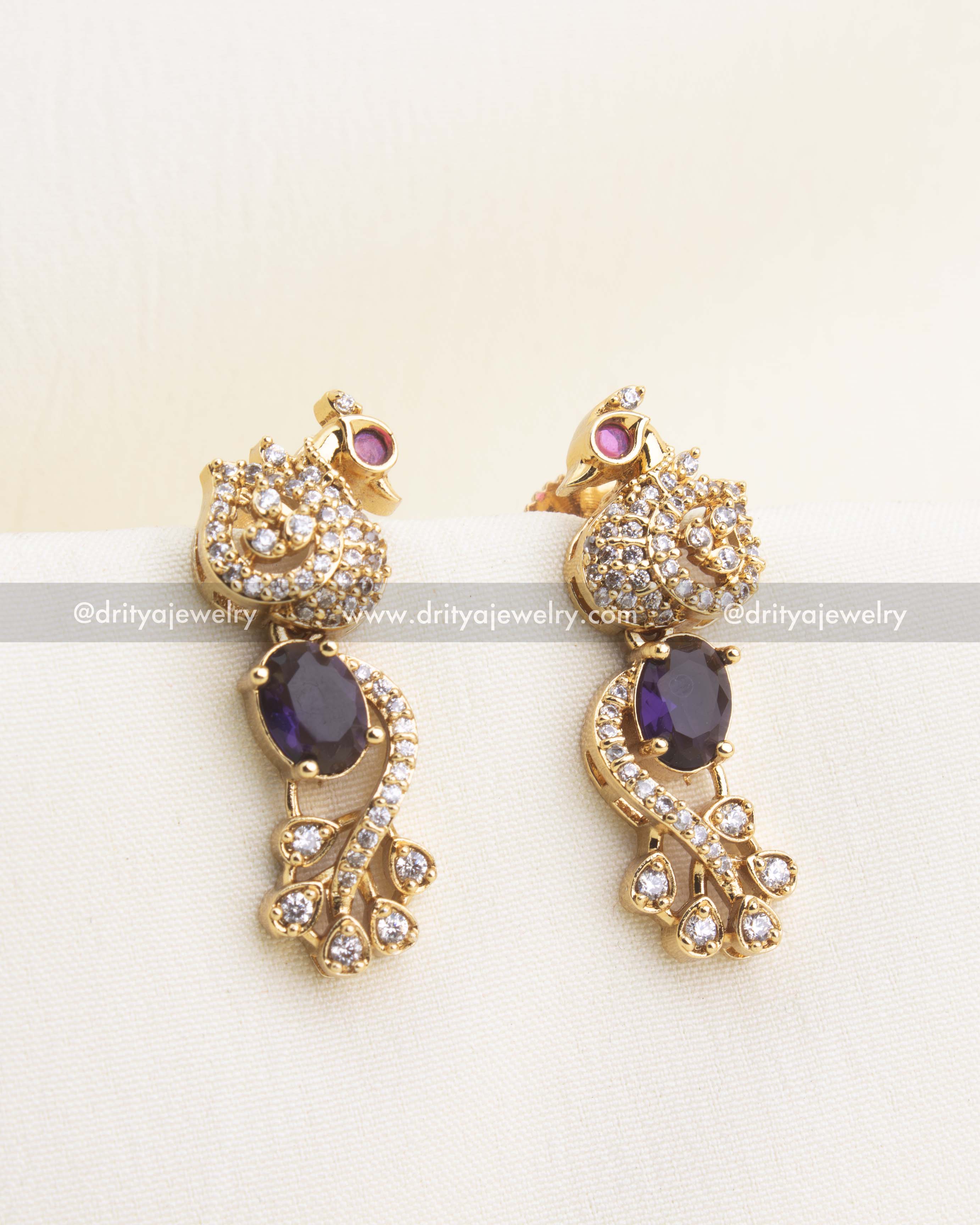 Purple earrings with peacock motif and sparkling CZ highlights.