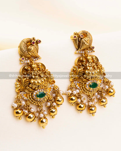 Pair of matching antique gold jhumka earrings featuring parrot motifs, green oval stones, and pearl-bead hangings.