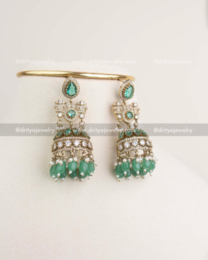 Matching big-size jhumka earrings with Russian emerald stones, AD crystals, and dangling green beads.