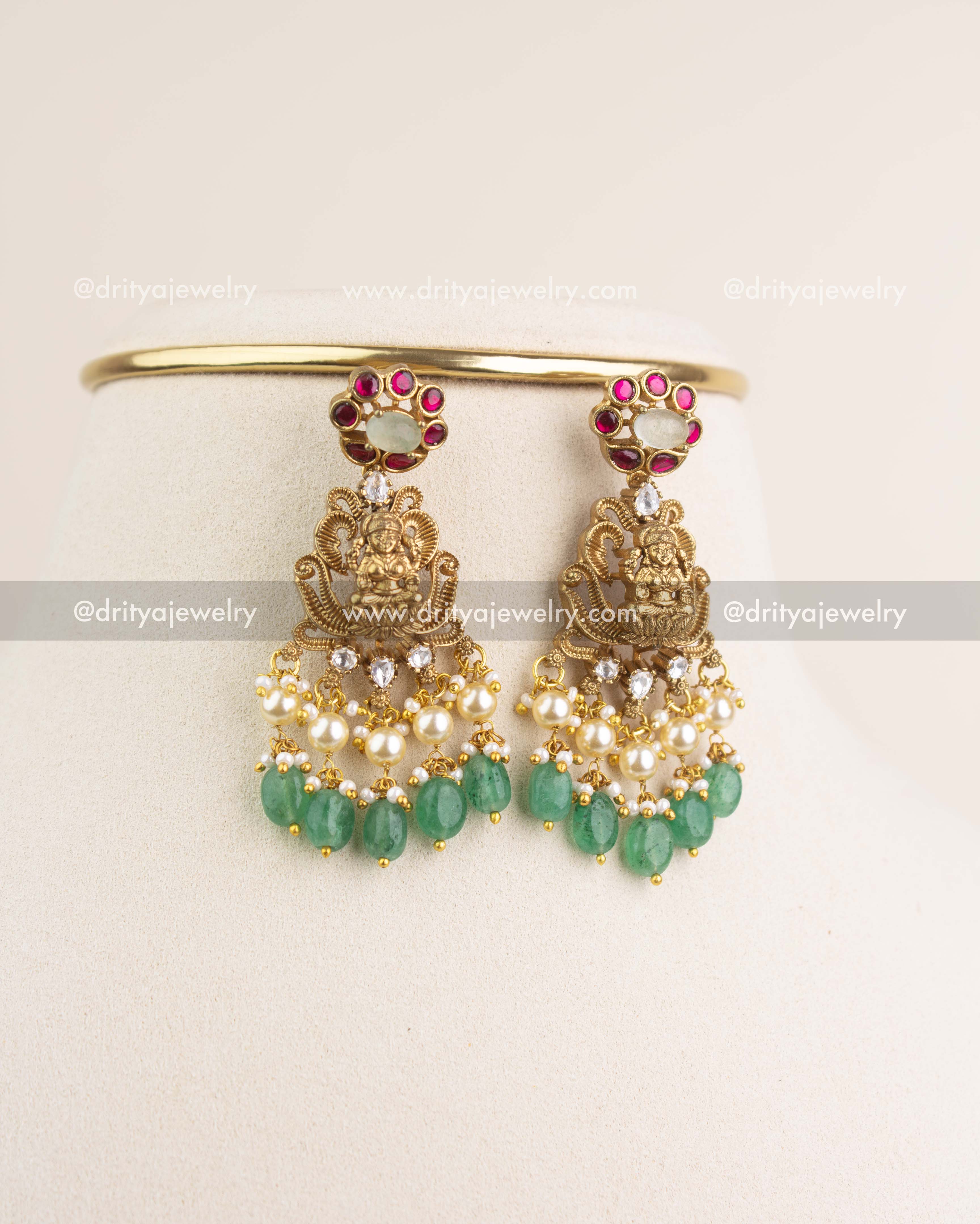 Matching Lakshmi Devi earrings with kemp stones, kundan, pearls, and green bead hangings.
