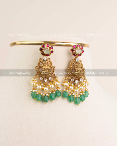 Matching Lakshmi Devi earrings with kemp stones, kundan, pearls, and green bead hangings.