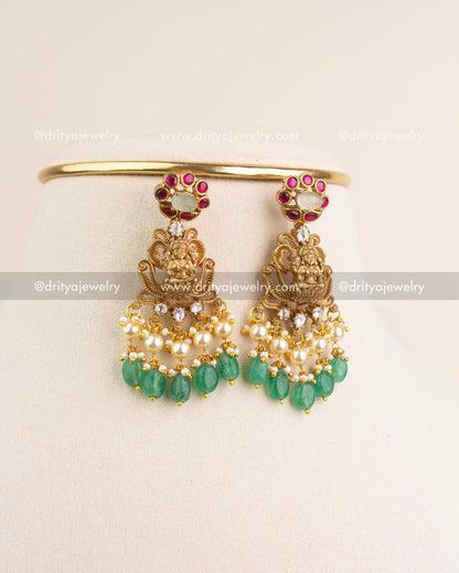 Matching Lakshmi Devi earrings with kemp stones, kundan, pearls, and green bead hangings.