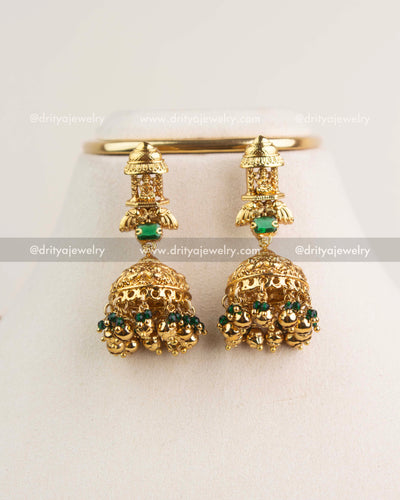 Pair of antique Nakshi jhumkas with green stones and gold bead clusters.