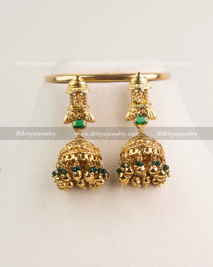 Pair of antique Nakshi jhumkas with green stones and gold bead clusters.