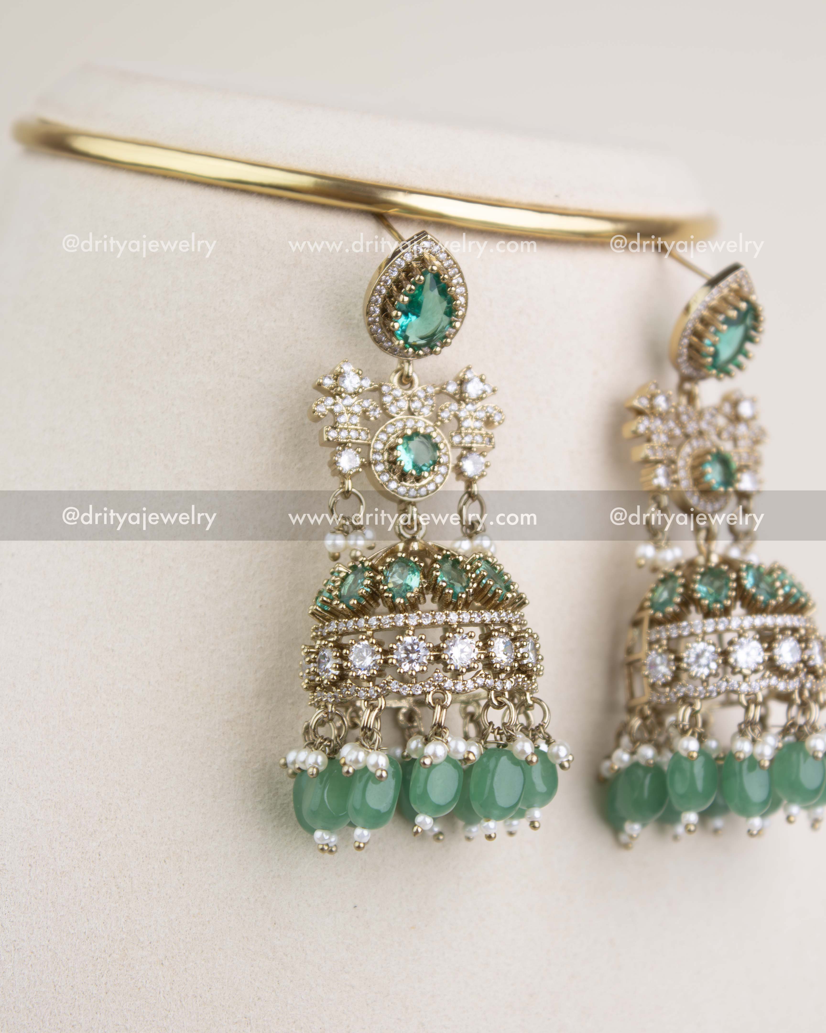 Matching big-size jhumka earrings with Russian emerald stones, AD crystals, and dangling green beads.
