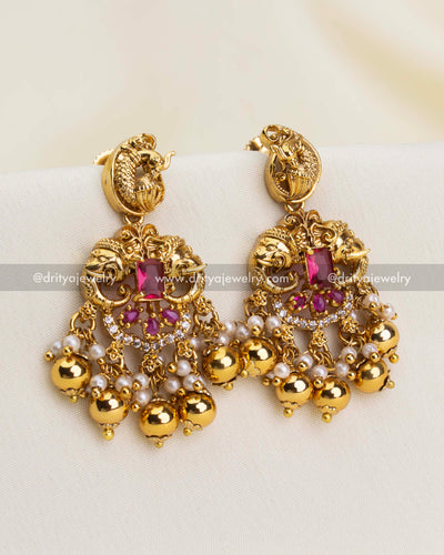 Matching earrings with yali face, peacock design, ruby stones, pearls, and gold beads.