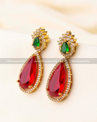 Elegant drop earrings with green top stones and ruby red teardrop dangles in gold finish.