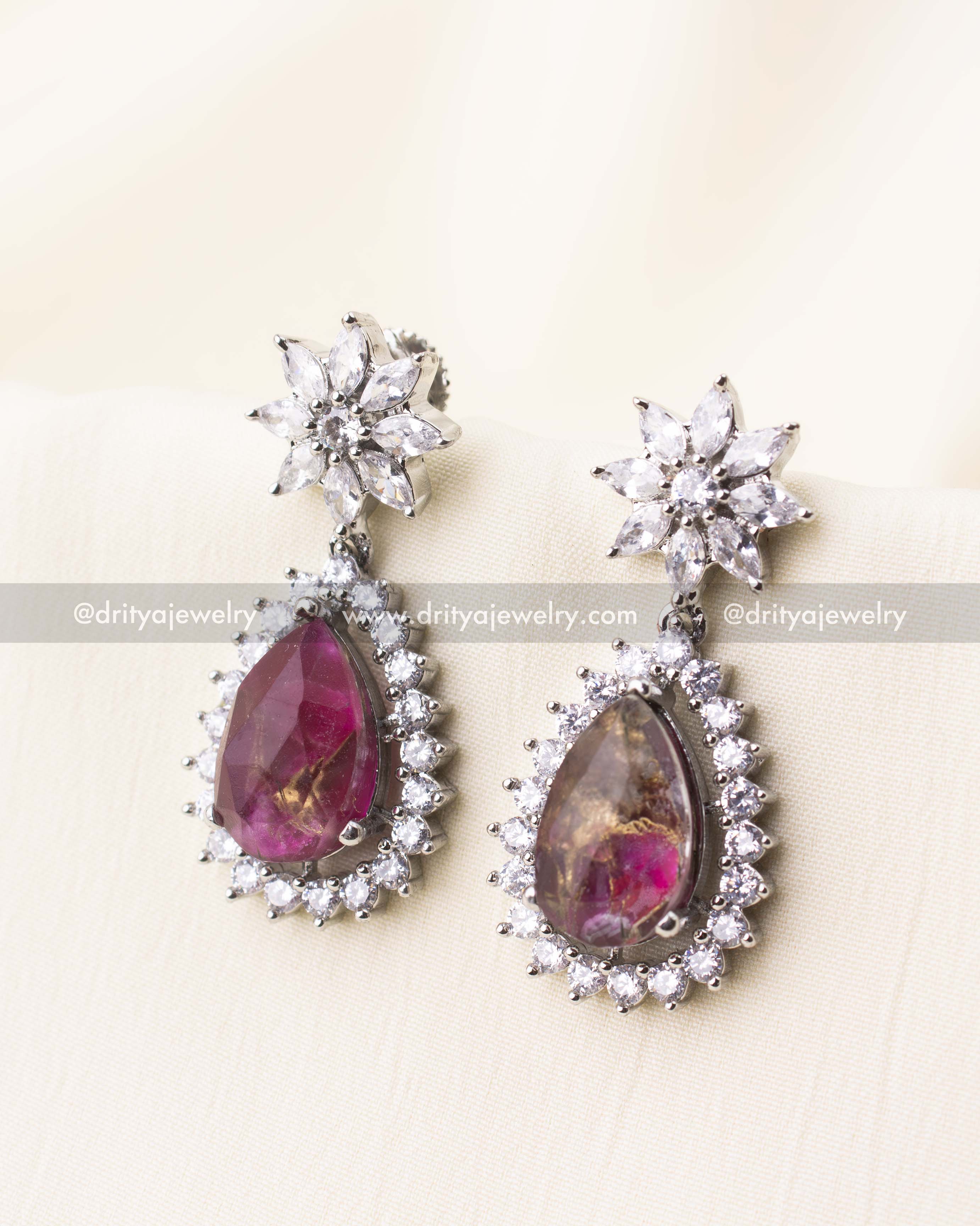 Teardrop earrings with deep pink stones and crystal-studded floral tops.