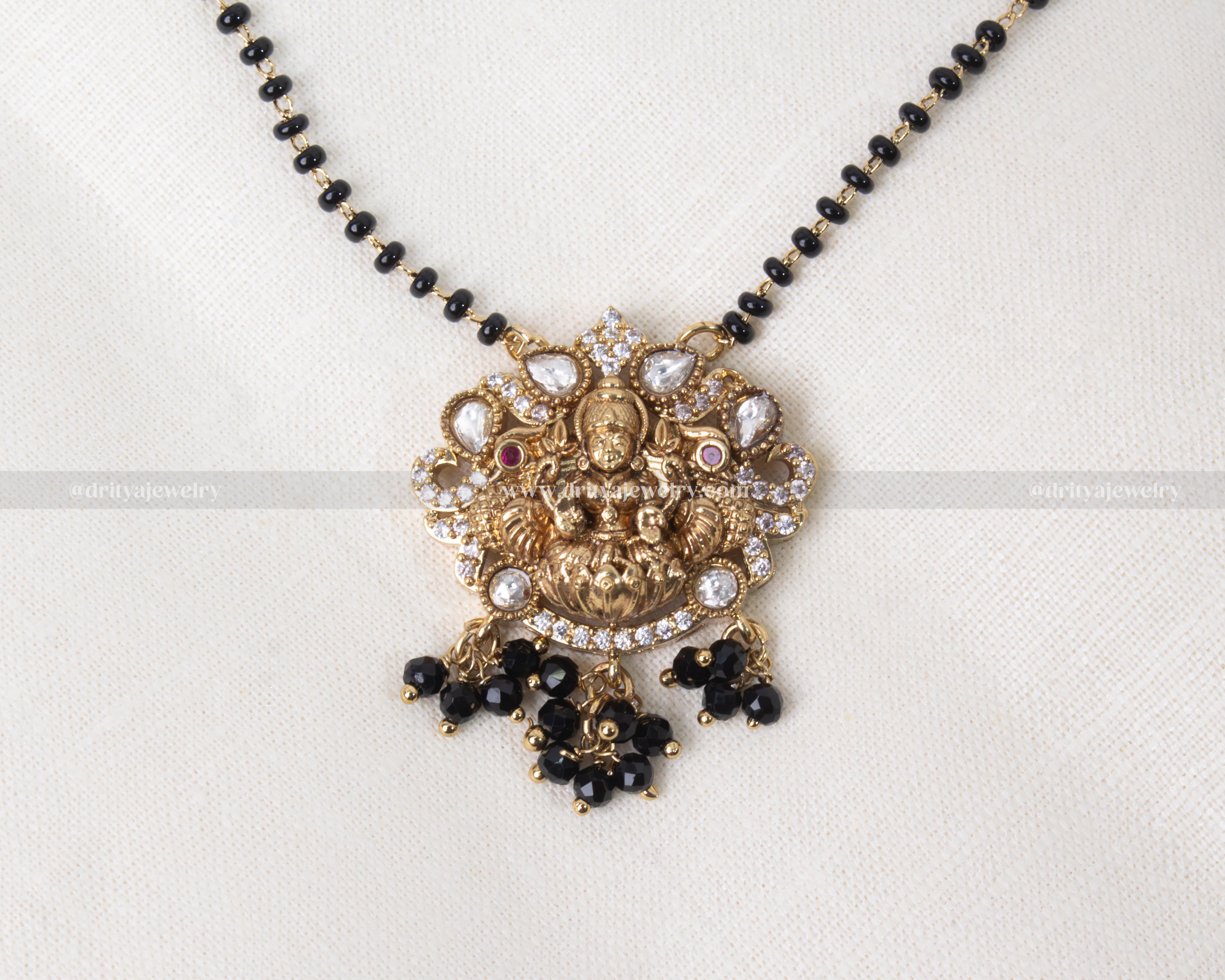 Traditional black beads necklace with gold-plated Lakshmi Devi pendant adorned with Kundan stones, perfect for cultural celebrations and everyday elegance.