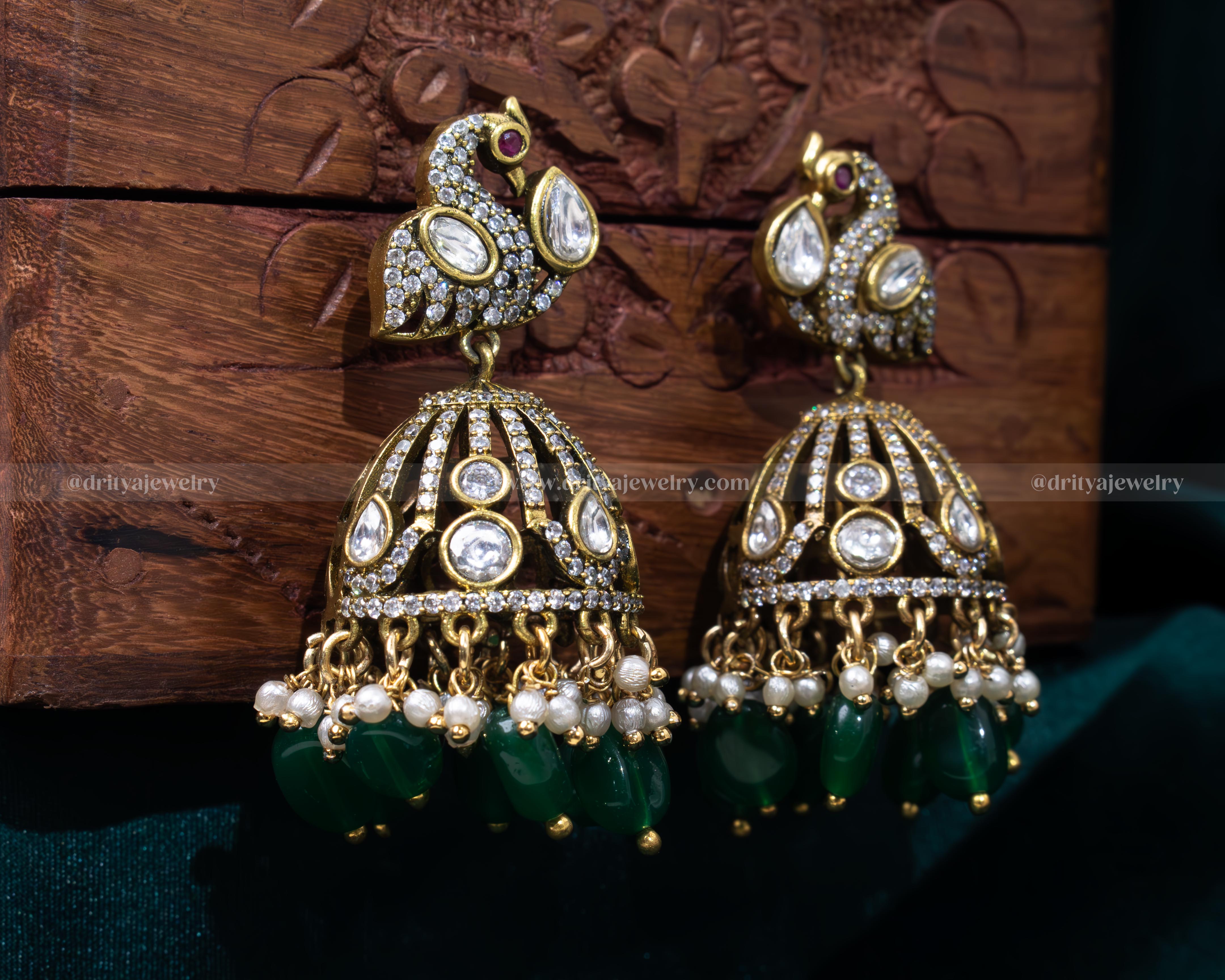 Luxurious emerald green Victorian jhumka earrings with faux gemstones and pearl accents, perfect for weddings and cultural festivities.