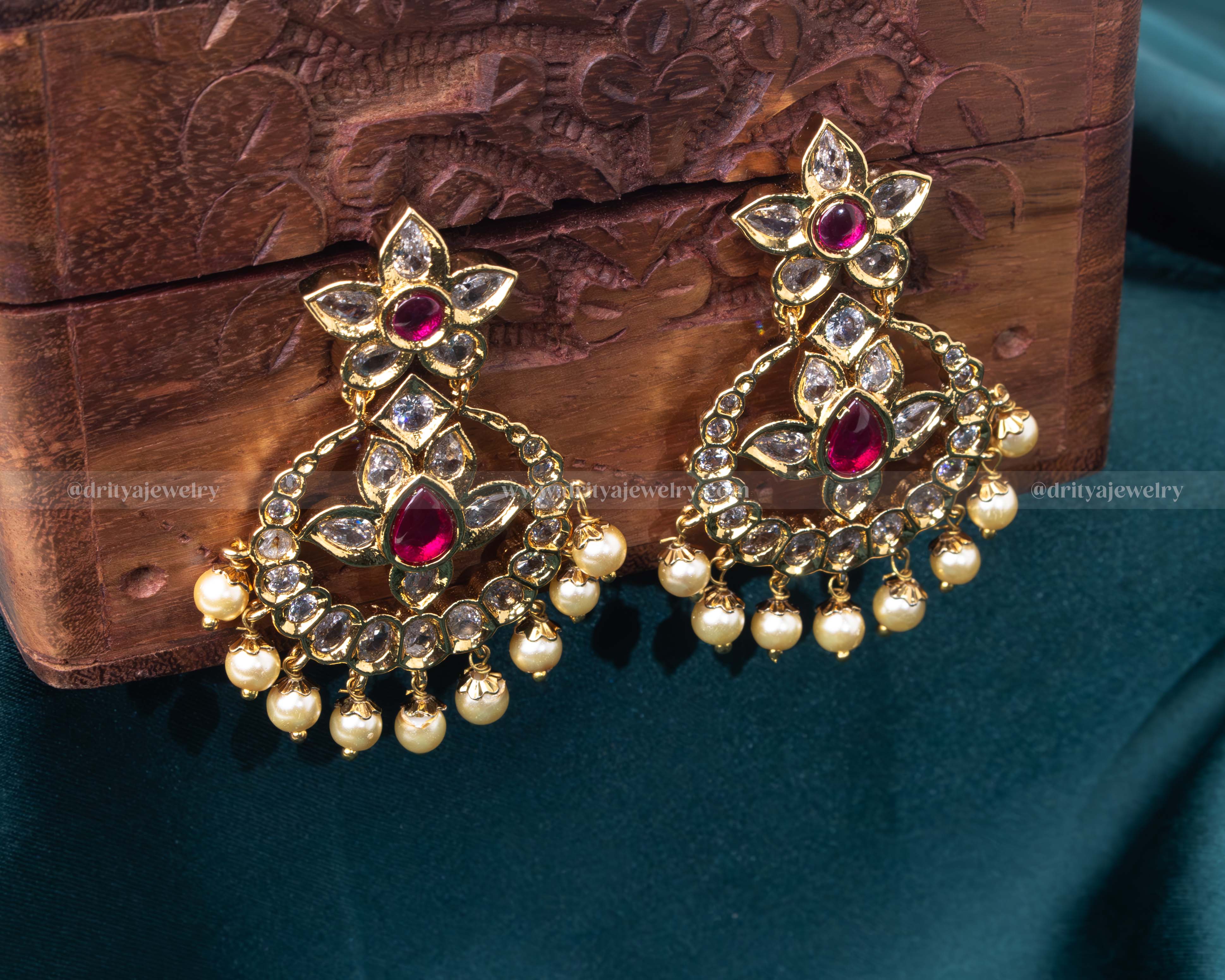 Intricate gold chandbali earrings with ruby, pearl, and kundan embellishments, ideal for weddings and formal events.