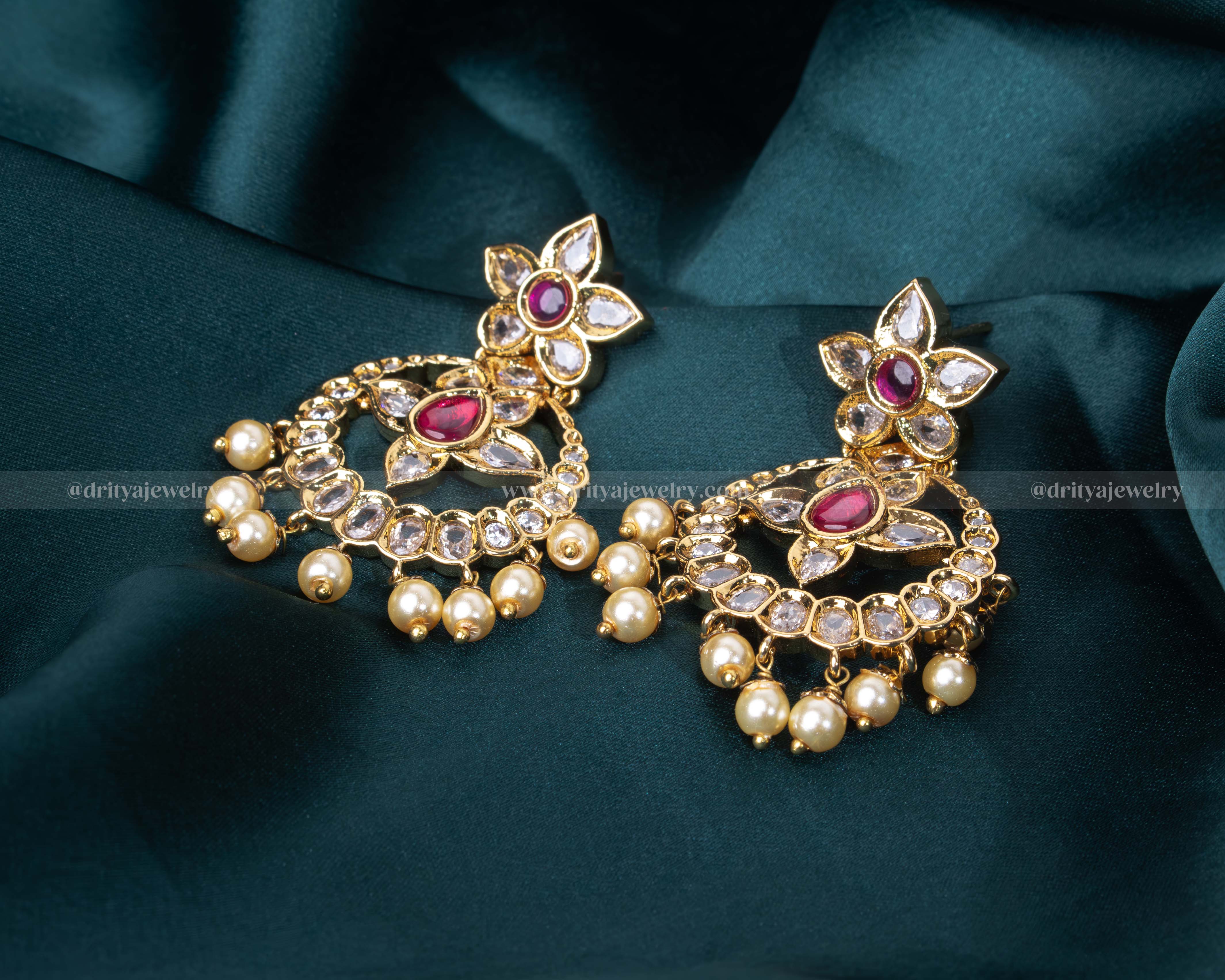 Intricate gold chandbali earrings with ruby, pearl, and kundan embellishments, ideal for weddings and formal events.