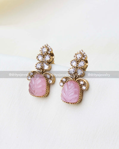 Matching stud earrings with carved pink stones and AD detailing for a coordinated look.