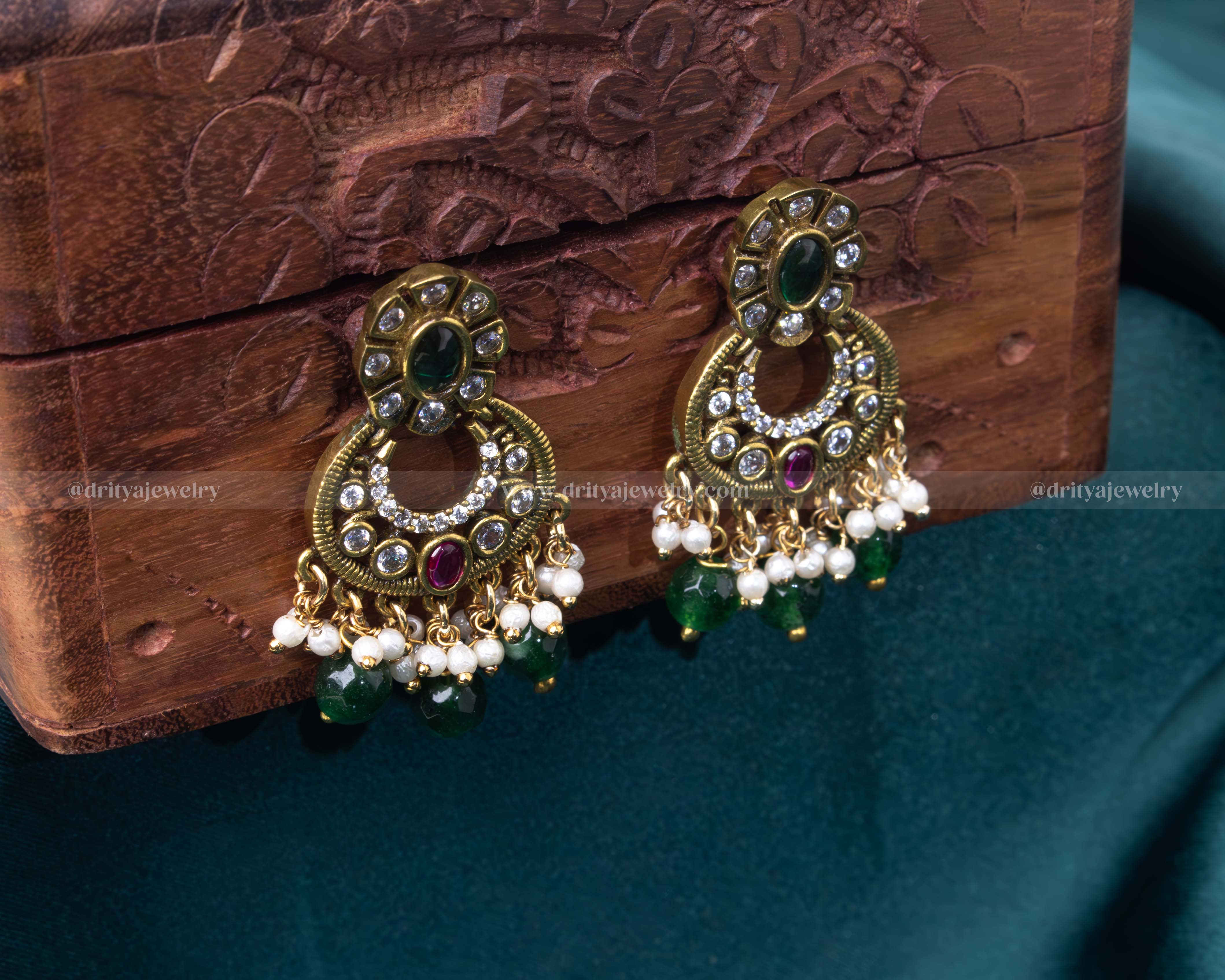 Victorian-style Chandbali earrings with uncut stones, green and ruby accents, and pearl drops.