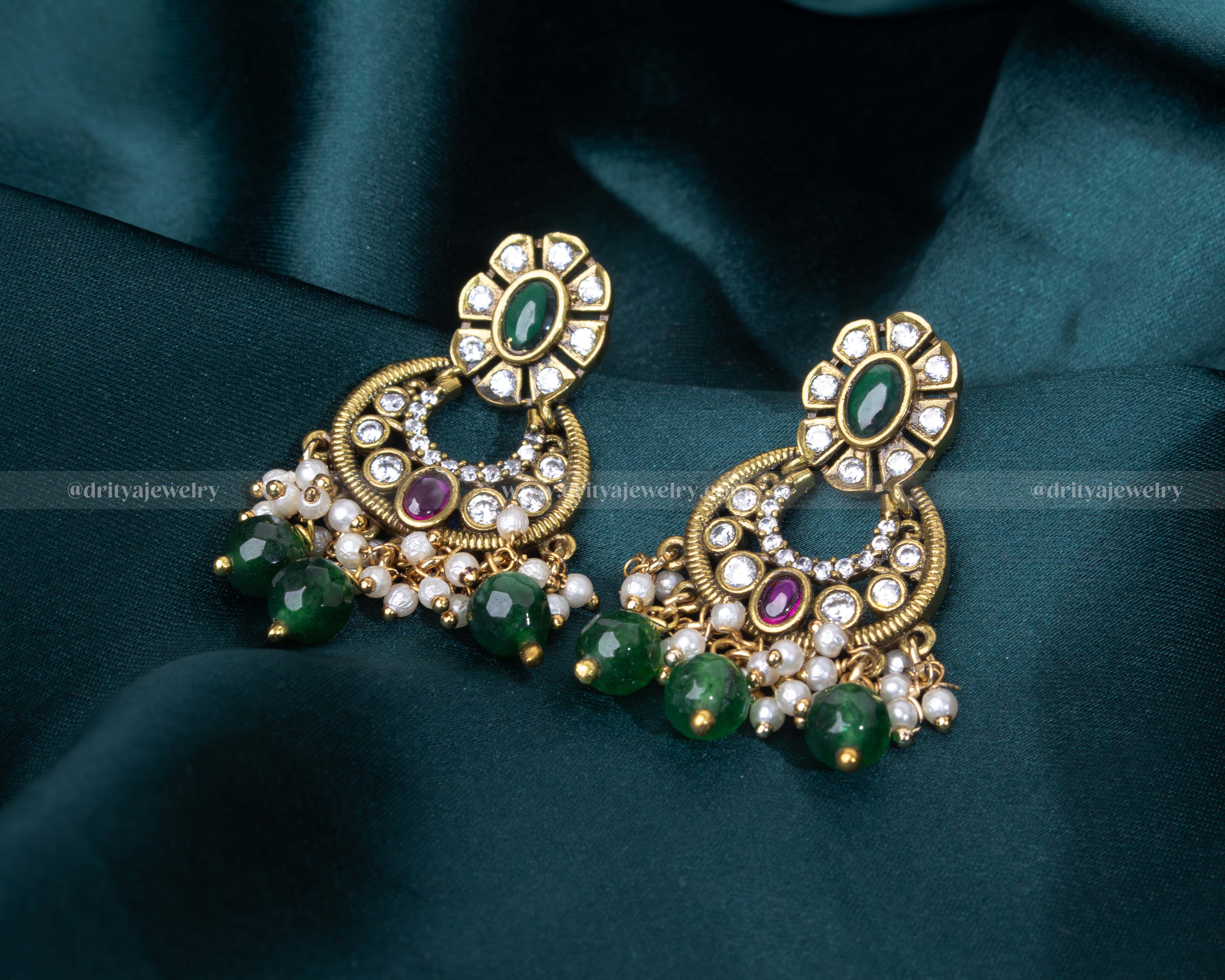 Victorian-style Chandbali earrings with uncut stones, green and ruby accents, and pearl drops.