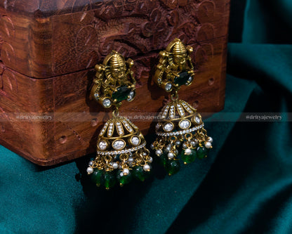 Intricate Victorian jhumka earrings with Lord Ganesh motif and emerald green beads, perfect for spiritual and festive occasions.