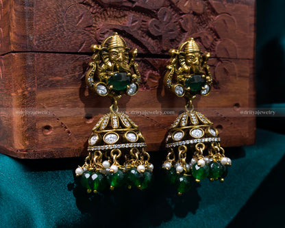 Intricate Victorian jhumka earrings with Lord Ganesh motif and emerald green beads, perfect for spiritual and festive occasions.